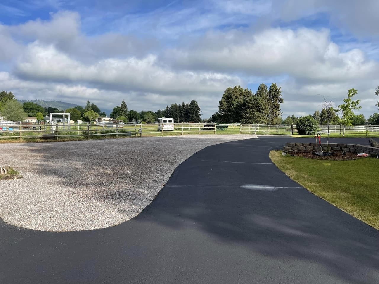 Finished curved asphalt driveway beside a rural property